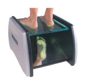 Los pies de una persona sobre el vidrio resistente de un podoscopio en forma de caja de madera con iluminación de colores y espejo.