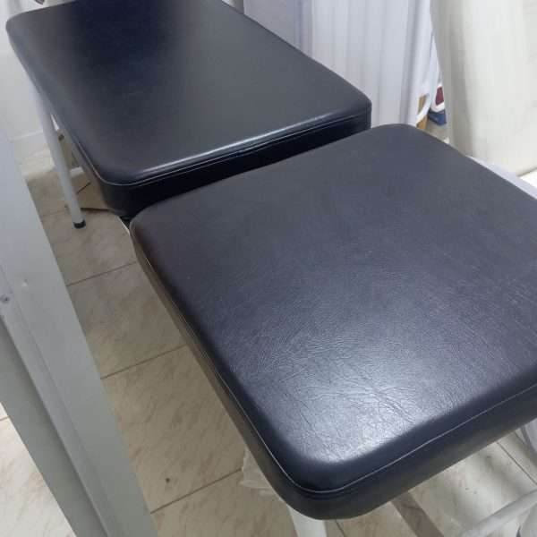 Colchoneta negra de alta densidad y resistente, sobre camilla diván fija para examen médico.